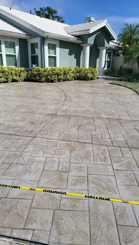 A wide stamped concrete driveway installation running from the street up to a two-car garage.